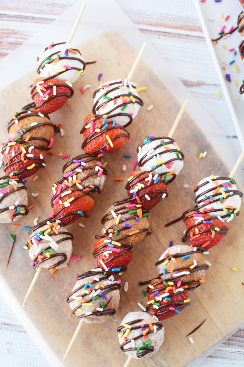 Donut kabobs lined up on a table.