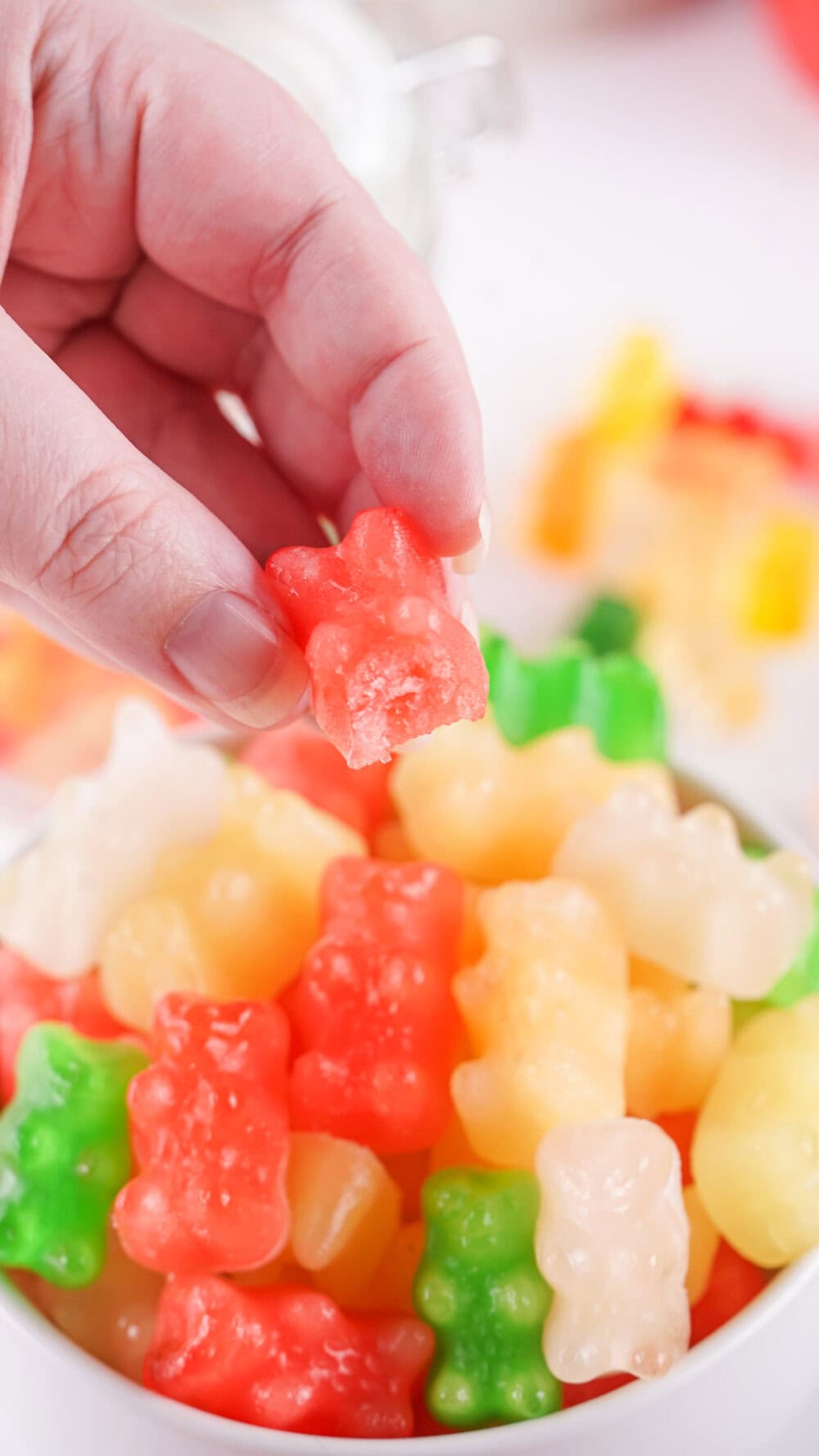 Holding a frozen gummy bear with a bite taken out of it.