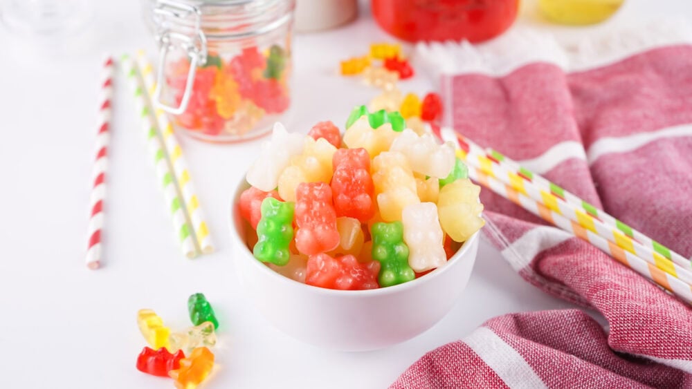 Bowl of frozen gummy bears with straws on the table.