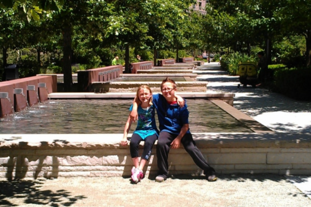 Two kids in front of a fountain.