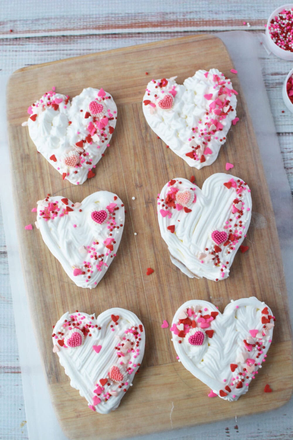 Whipped cream hearts with sprinkles on a board. 