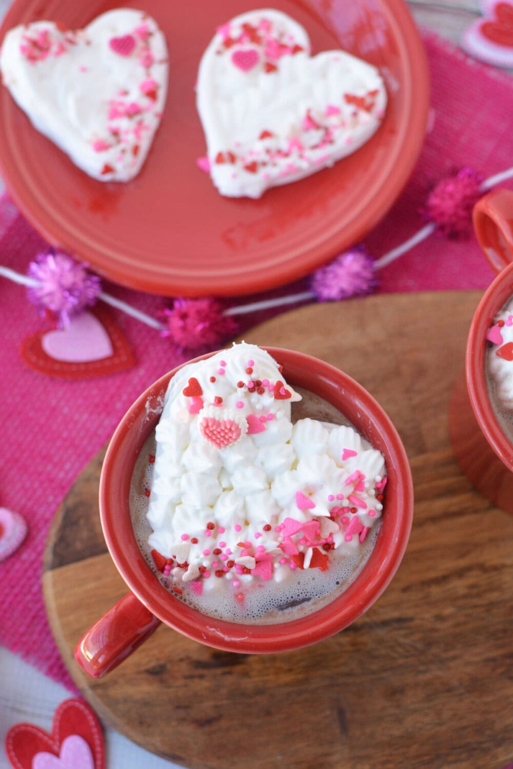 Heart whipped cream topper in a mug and 2 on a plate. 