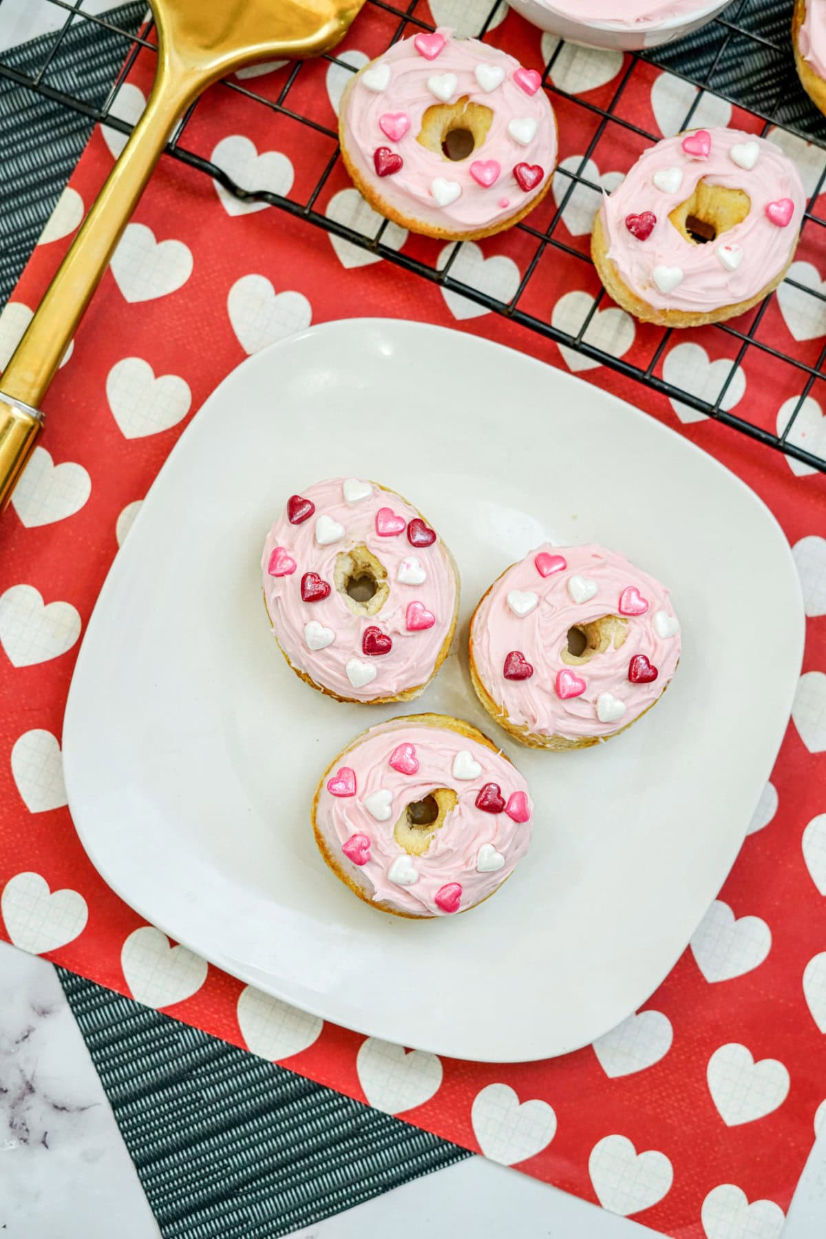 Three mini donuts on a plate next to a gold spatula.