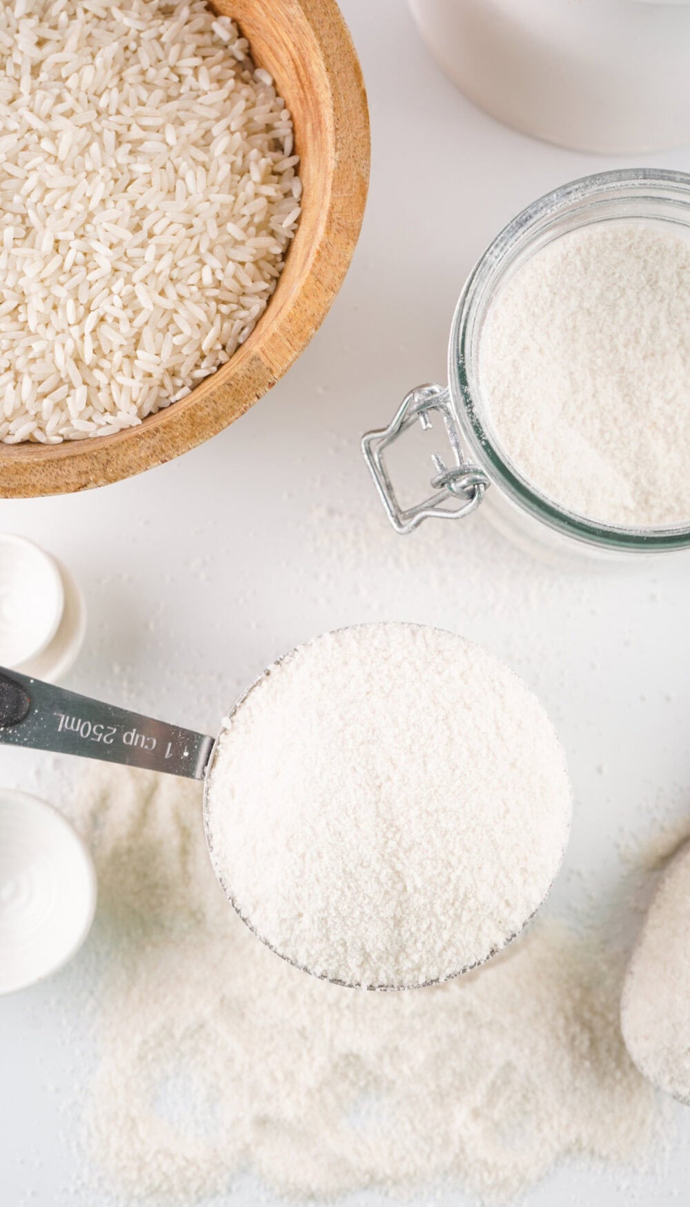 Rice flour in a cup next to a bowl of rice.