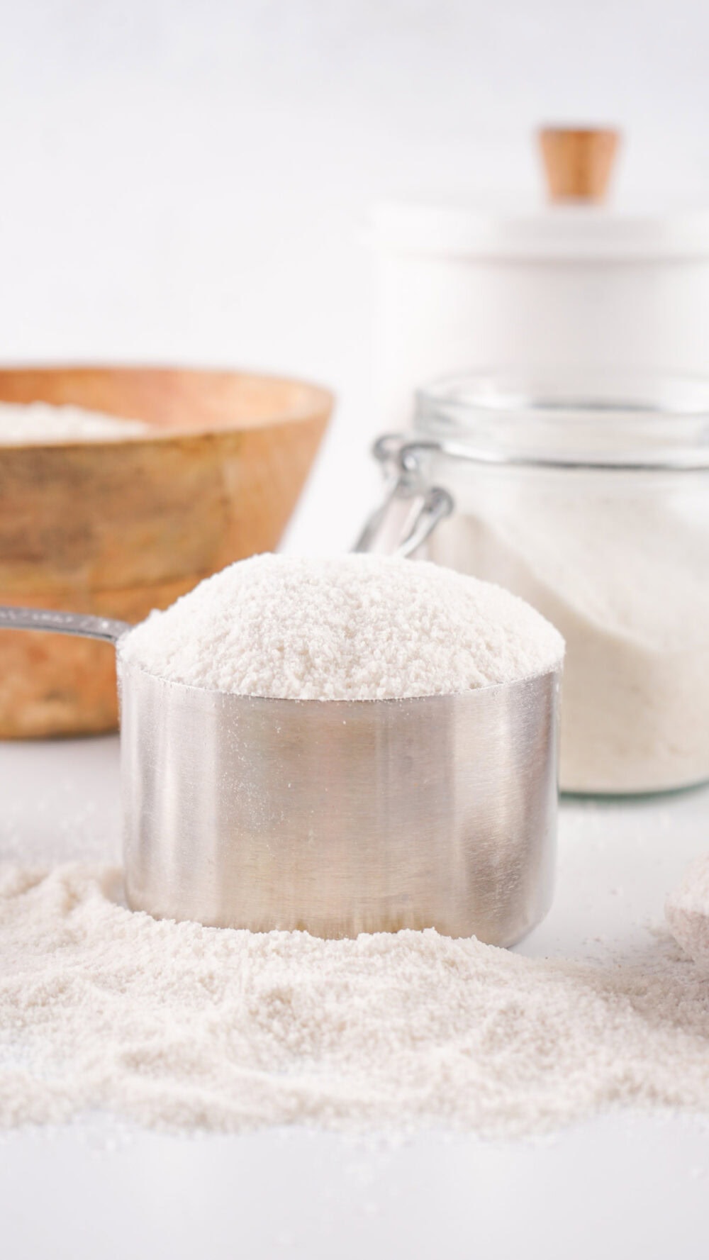 Rice flour in a measuring cup with some on the table.