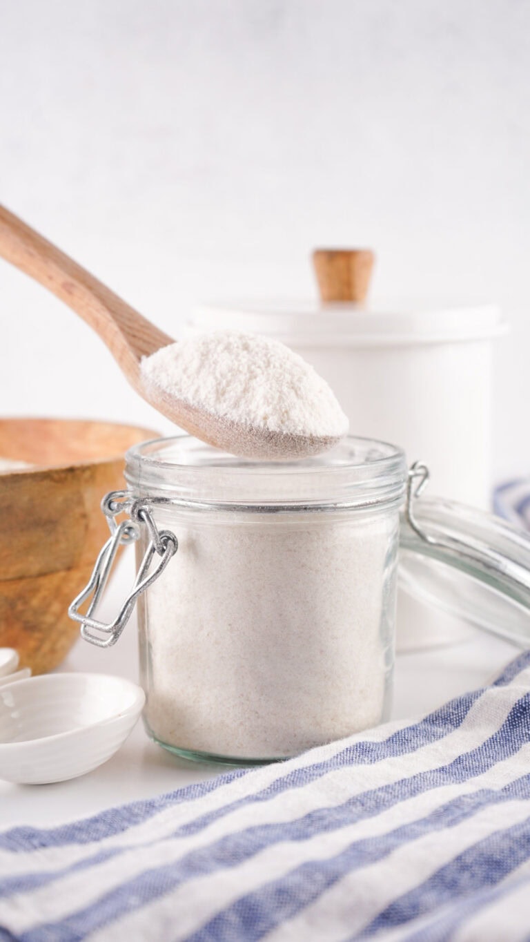 Spoon scooping out rice flour from a glass jar.