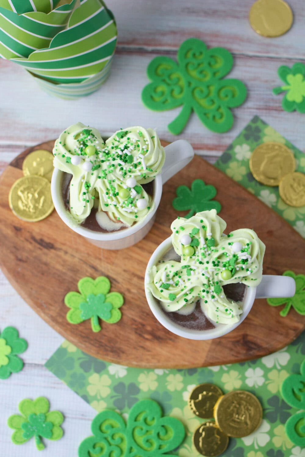 Two mug of hot chocolate with St. Patrick's day whipped cream toppers.