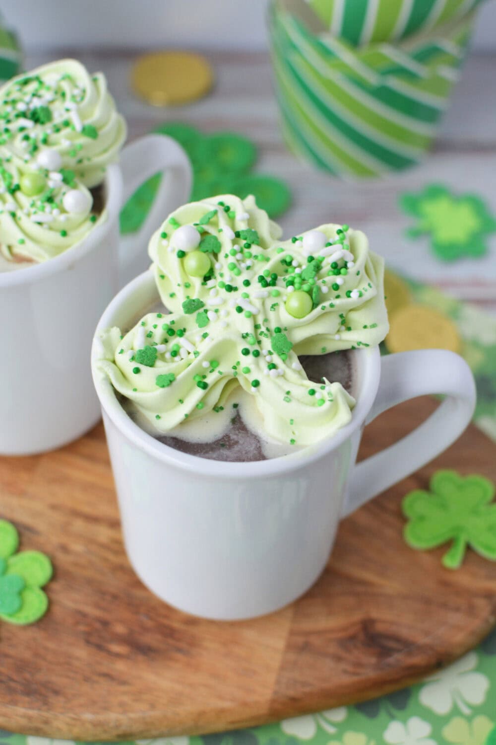 Green shamrock frozen whipped cream on top of a mug of hot chocolate.