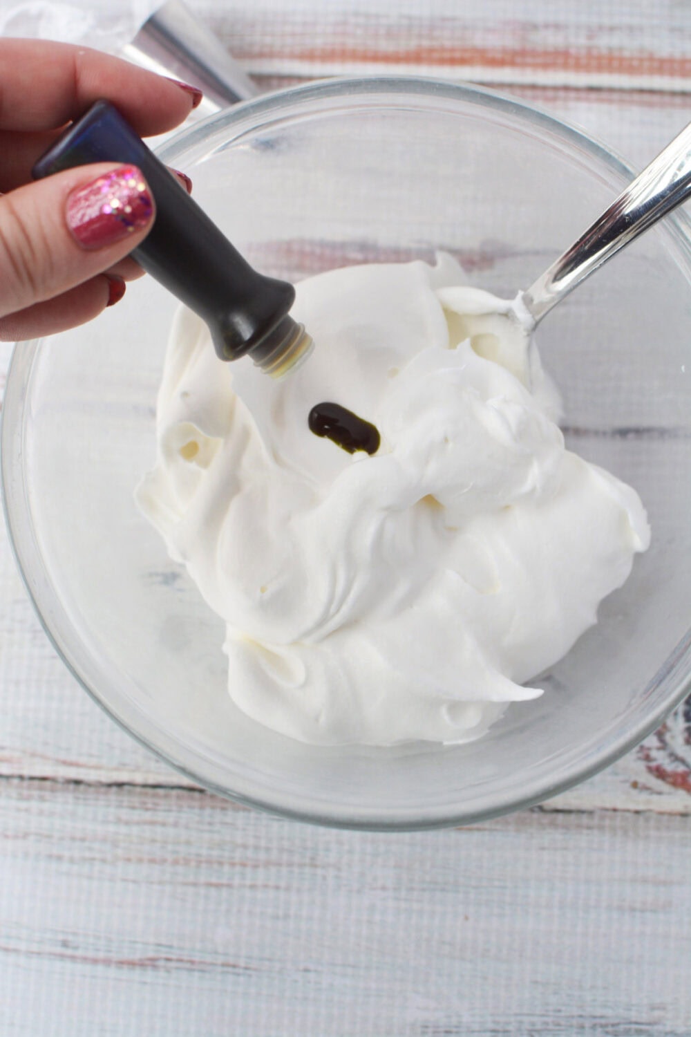 Adding green food coloring to whipped topping in a bowl. 