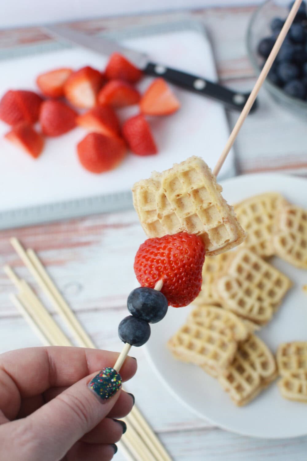 Adding berries and waffles to a skewer.