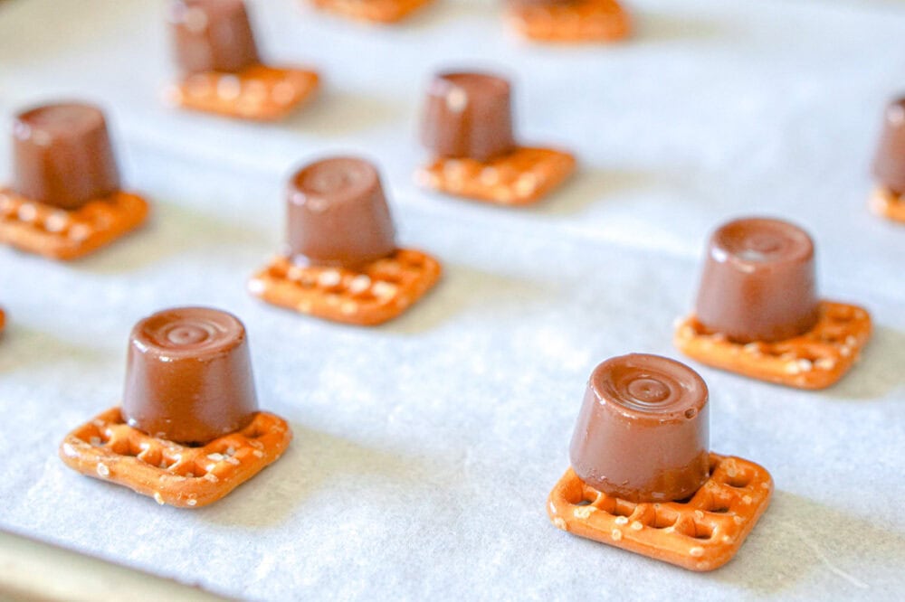 Pretzel snaps topped with Rolos on a baking sheet.