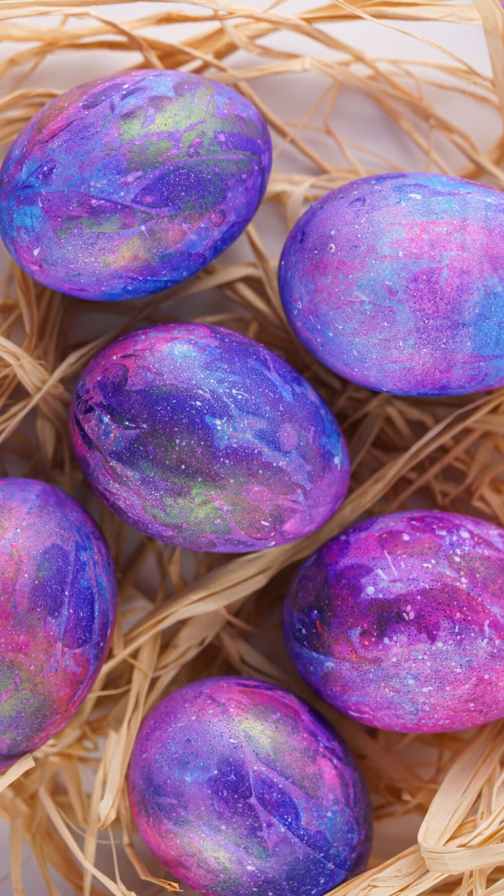 Galaxy colored Easter eggs in a bed of straw.