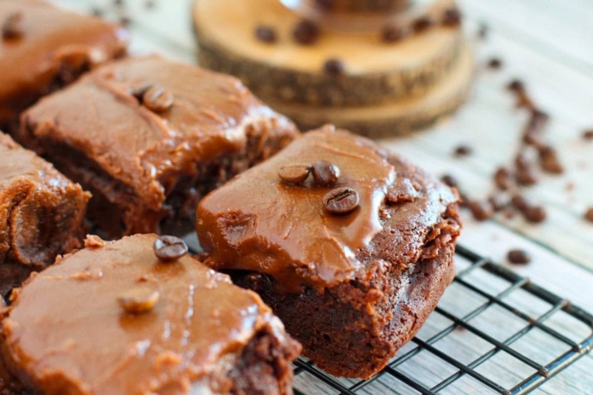 brownies with frosting and coffee beans on a rack