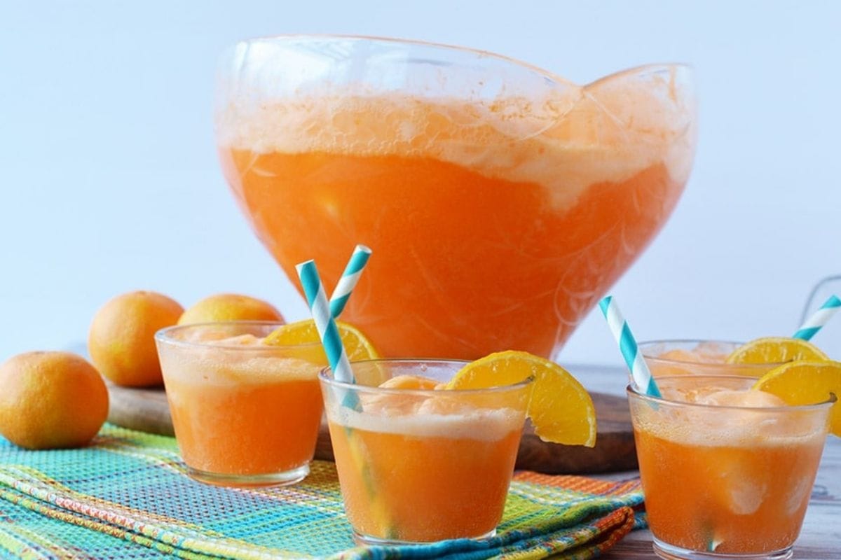 orange sherbet punch in bowl and glasses around it