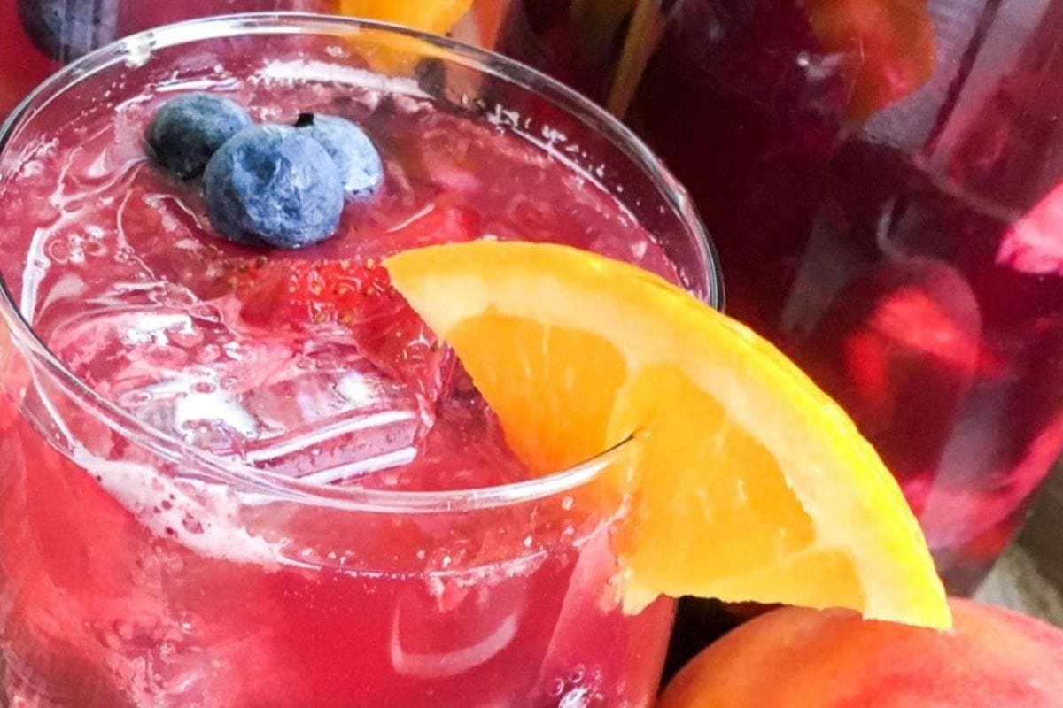 red drink with blueberries and an orange slice