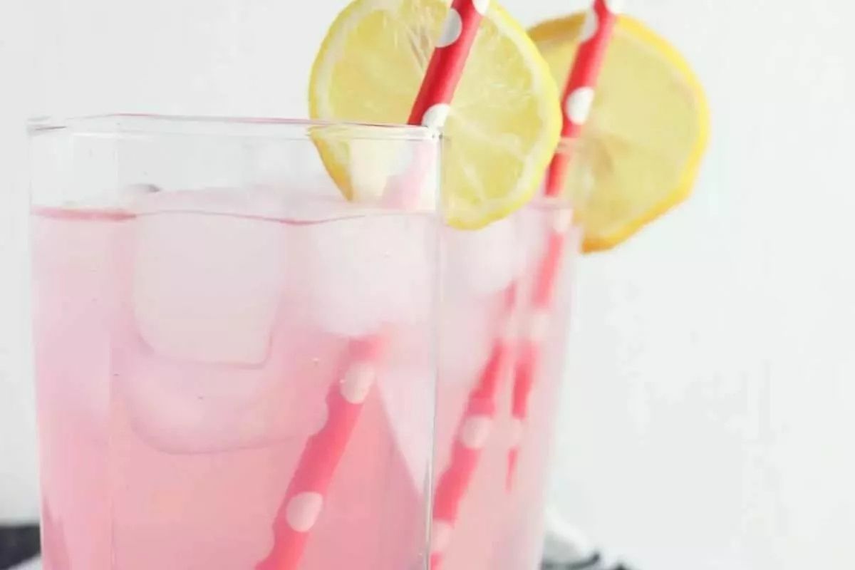 pink drink in a glass with ice and lemon