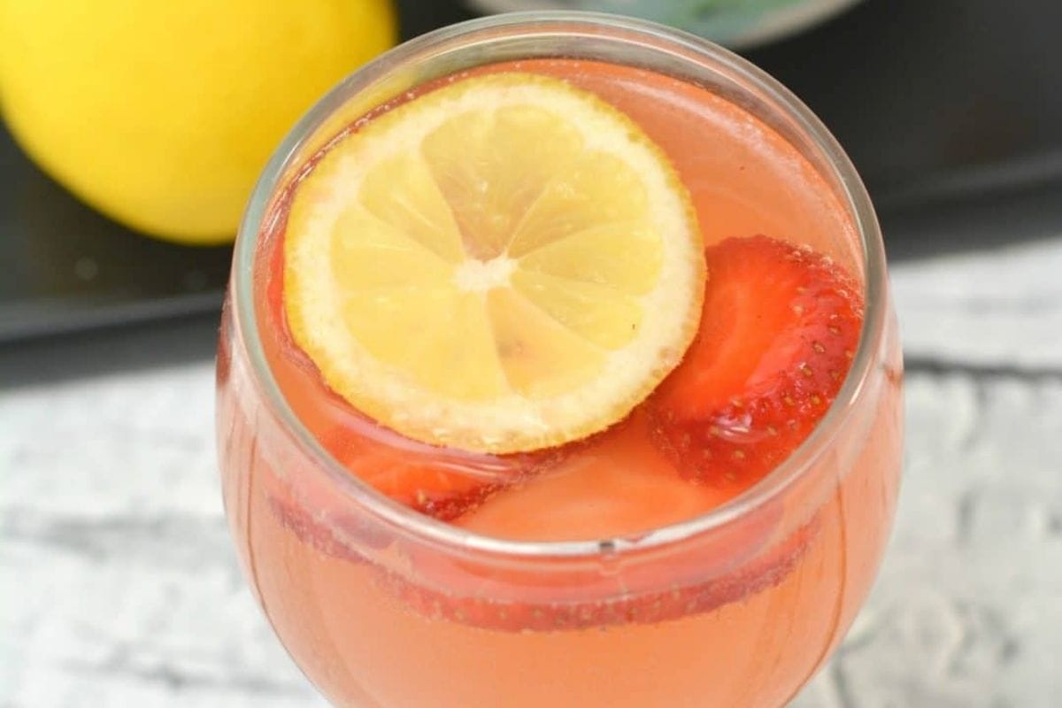 red drink in a glass with strawberry and lemon