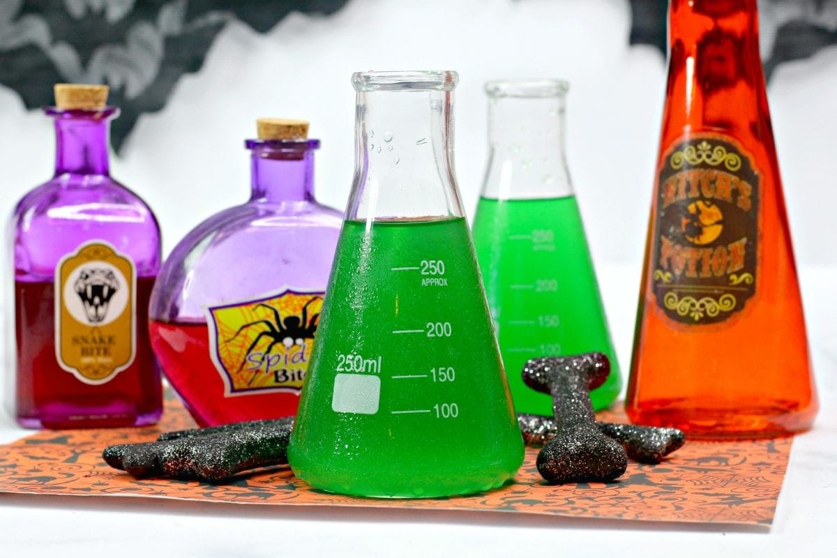 green punch in a beaker with Halloween decor around it