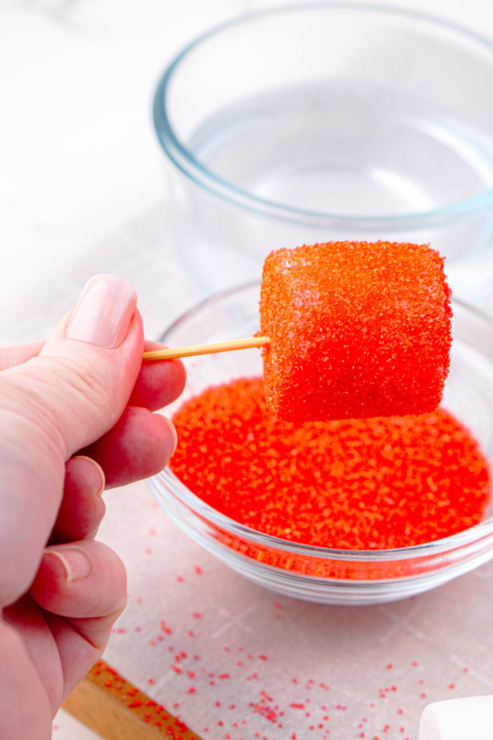 dipping a marshmallow into red sanding sugar