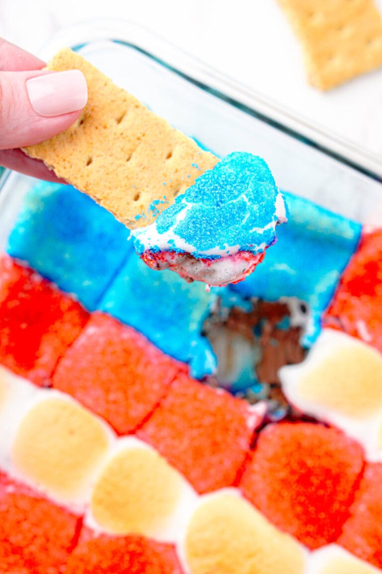 A graham cracker that's been dipped into flag smores dessert dip