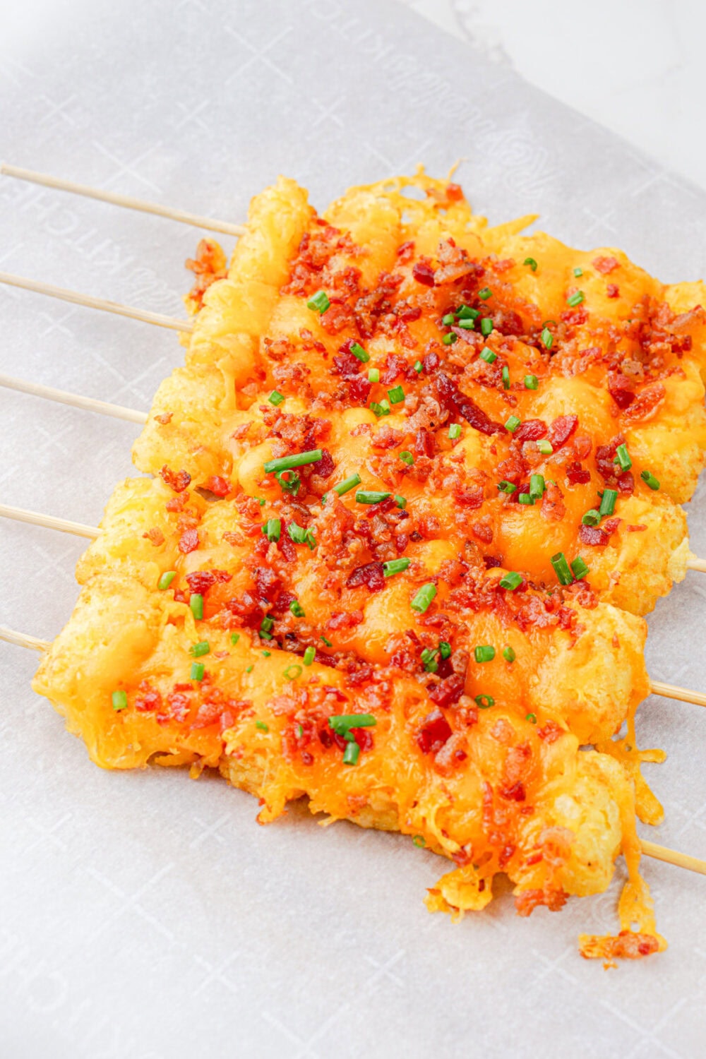 Tater tot skewers with bacon and cheese in a row