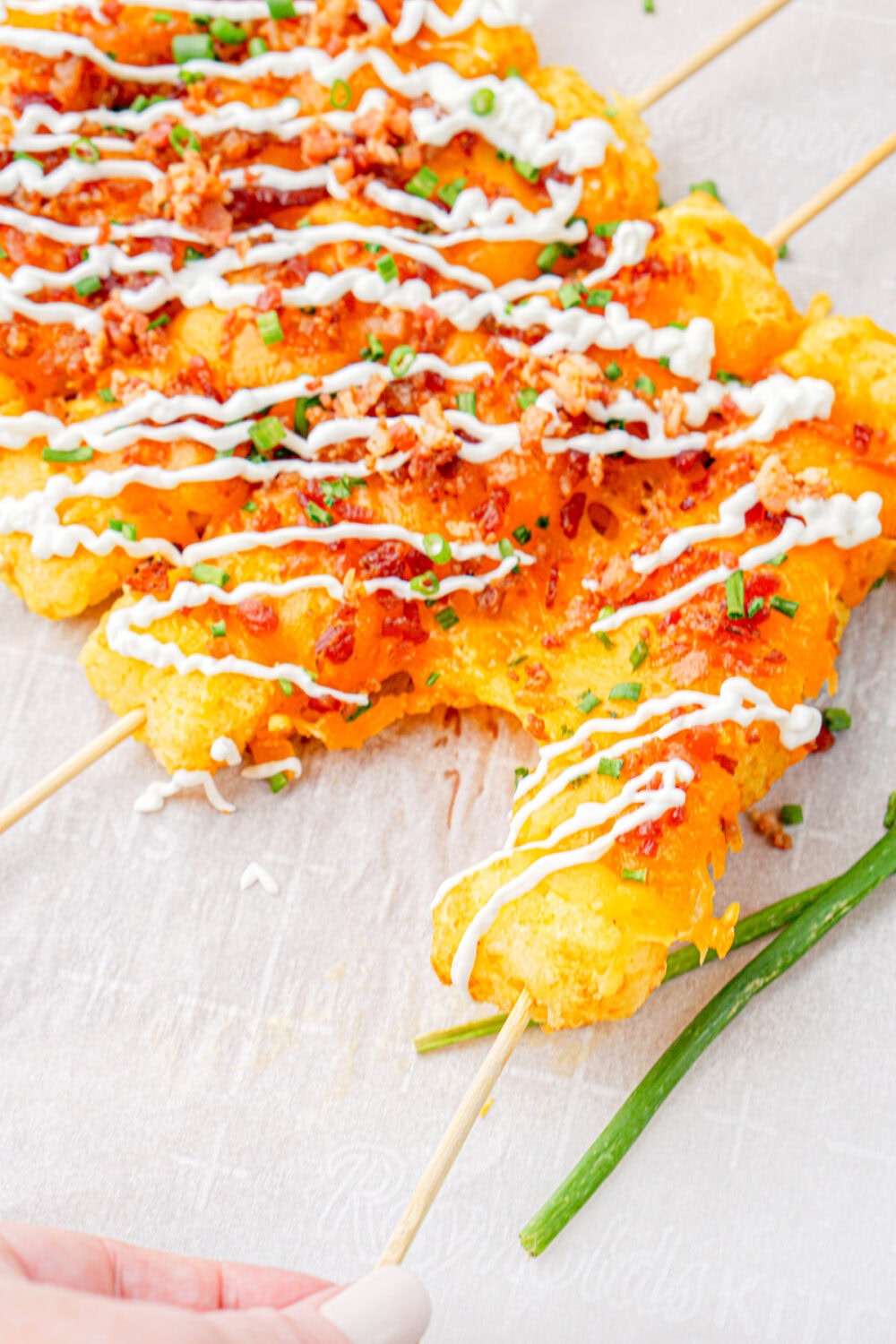Pulling a tater tot skewer with gooey cheese