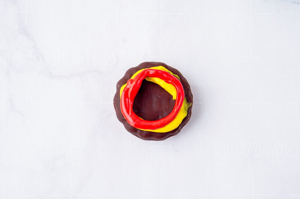 swirl of red icing on top of yellow icing on cookie