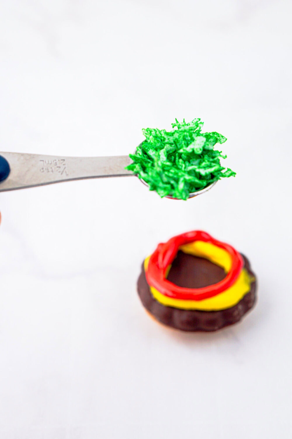 adding shredded green coconut to burger cookie