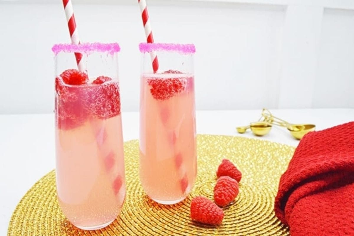 raspberry lemonade mimosas in rimmed glasses