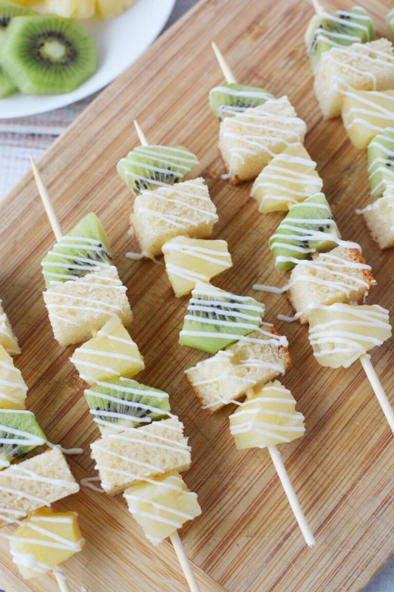 Pineapple, kiwi, pound cake dessert skewers on a board
