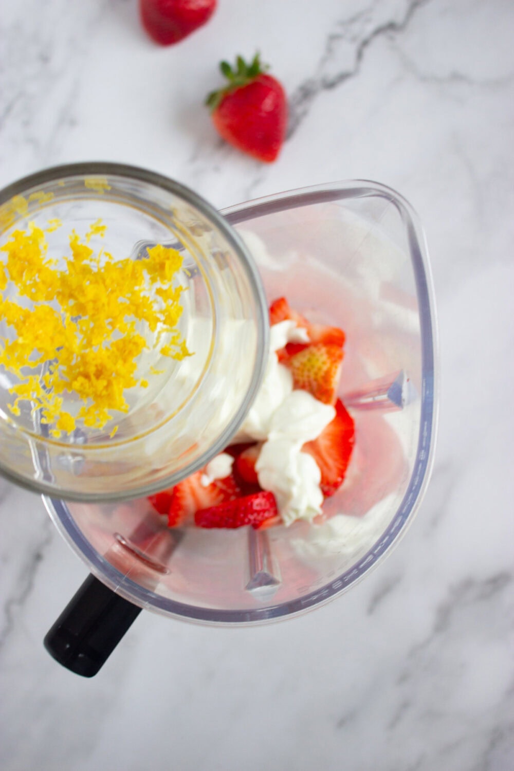 adding lemon zest to a blender with strawberry. mixture