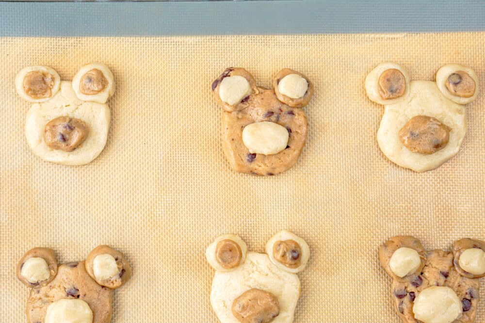 cookie dough bear faces on a baking sheet